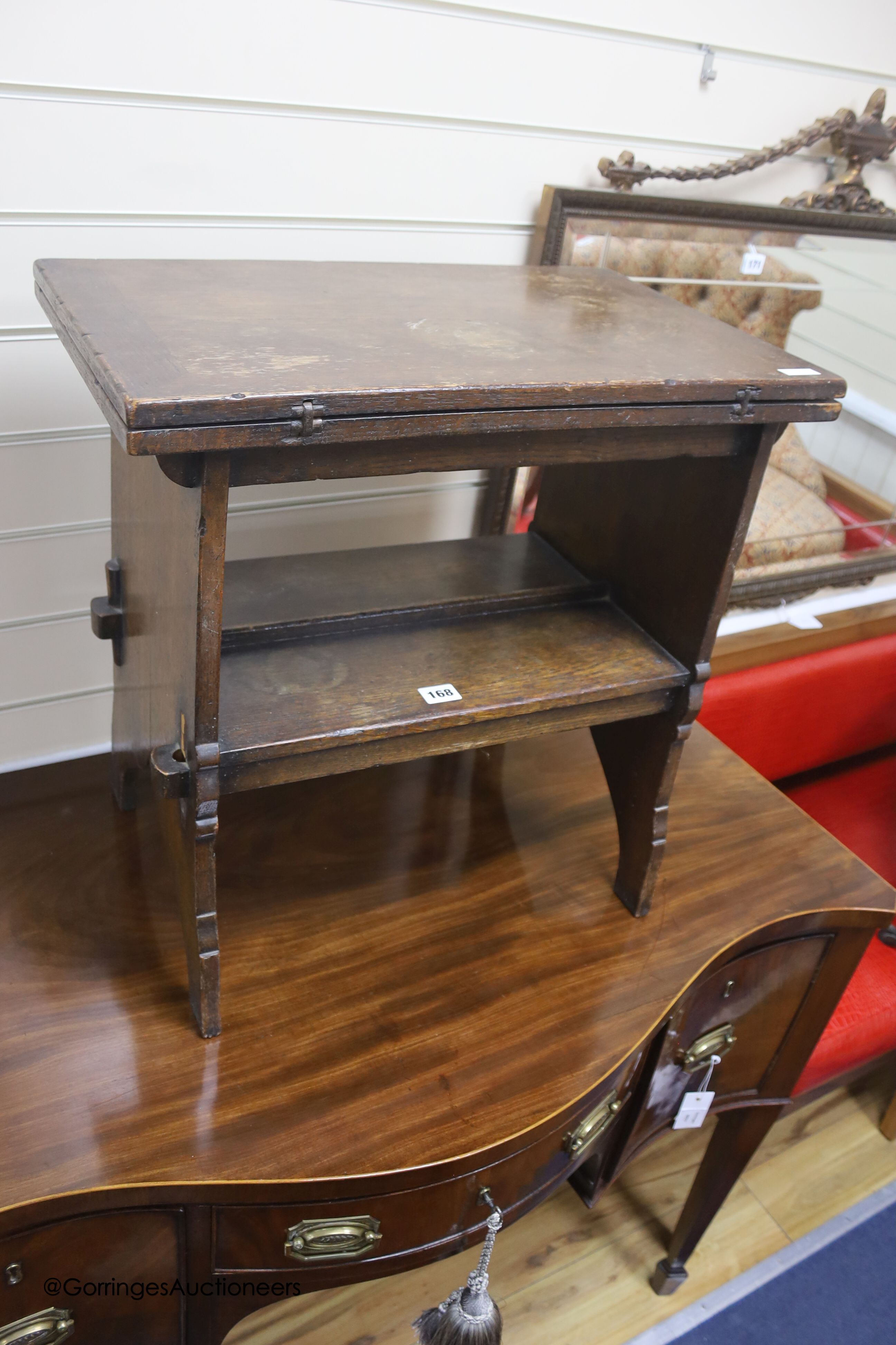 An early 20th century solid, dark oak occasional table with folding top and undertier